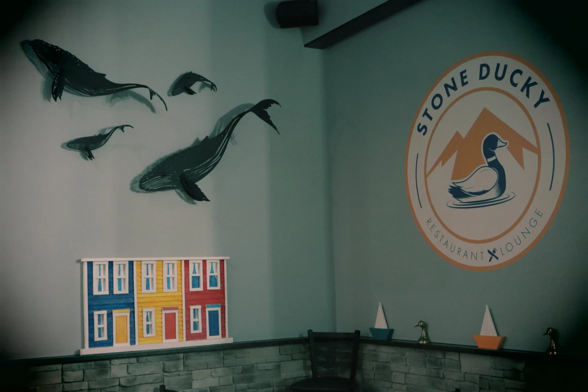 Corner view of inside Stone Ducky Restaurant with the logo and a whale mural on the wall